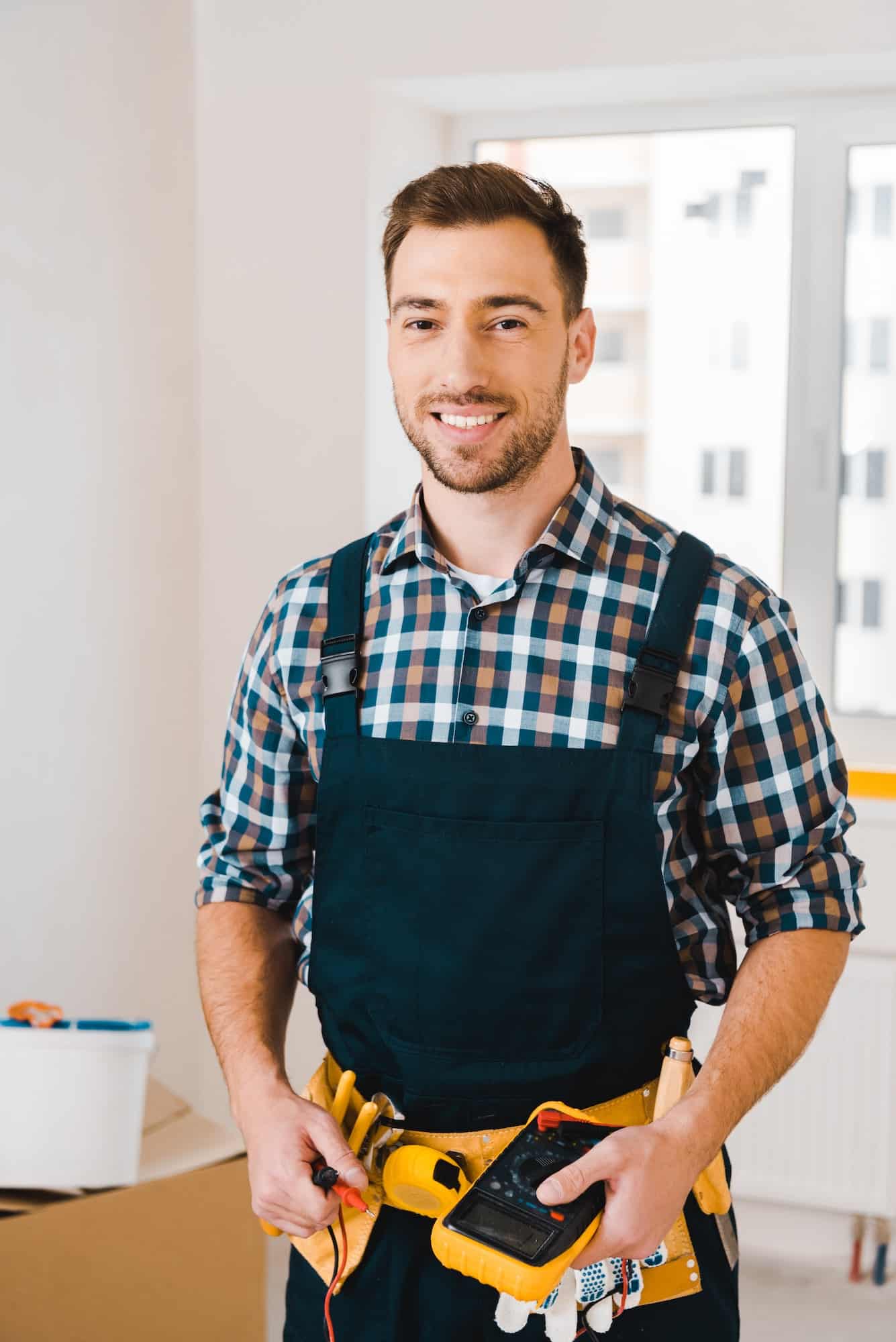 handsome-handyman-smiling-while-holding-digital-multimeter.jpg